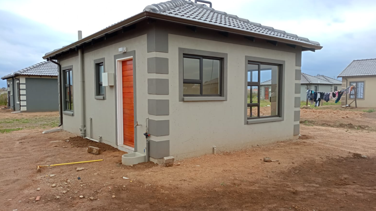 Two-bedroom Gable-roof starter home at WindmillPark with quoined corners and timber front door, photographed under overcast Highveld light.